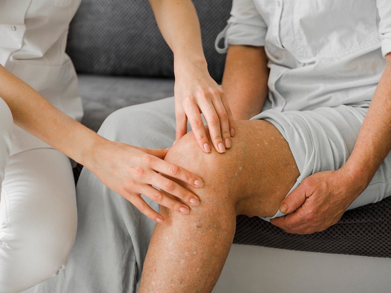 Physiotherapist examining a patient's knee